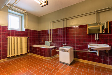 Vorher: altes Bad mit dunkelroten Fliesen und eingebauter Badewanne
